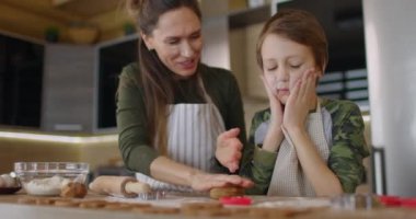 Genç anne ve oğlu mutfakta birlikte kurabiye pişiriyorlar. Anne ve bebek şekilli ev yapımı kurabiyeleri kestiler. Yakın çekim görüntüsü. Yavaş çekim