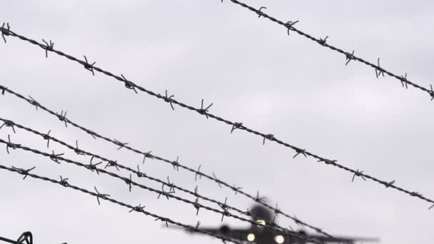 Airplane landing flies over barbed wire — Stock Video