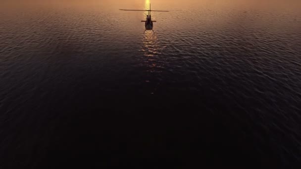 Elicopterul zboară deasupra mării la apusul soarelui — Videoclip de stoc