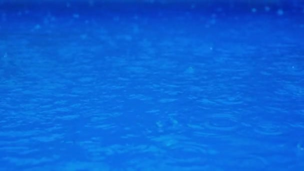 Slow motion video with droplets. Raining on a blue water. — Wideo stockowe