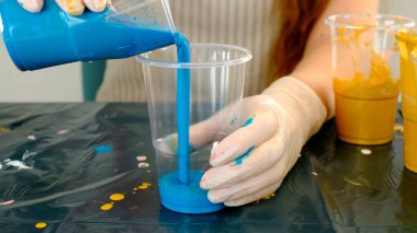 Fluid art technique. Female artist works on abstract fluid art painting.