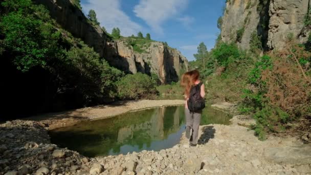 女人跑到水边去了女孩正在大自然中远足 绿色岩石景观 山地和池塘 美丽的峡谷 慢动作中的水平视频 — 图库视频影像