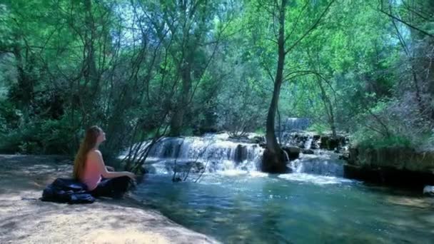 Kvinna Sitter Och Mediterar Natur Med Ett Vattenfall Vackert Landskap — Stockvideo
