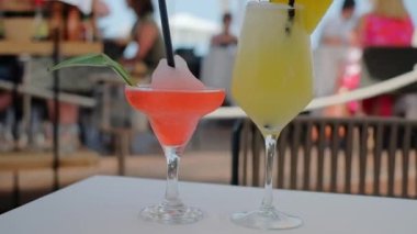 İki kokteyl yakın çekim. Pina colada kokteyli ve karpuz kokteyli. Ananaslı iç, hindistan cevizli ve romlu. Kadehte kamış. Yavaş çekim videosu.