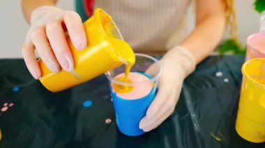 Bir sanatçı plastik bardakta akrilik renkleri karıştırıyor. Sıvı resim hazırlığı. Güzel soyut teknik.