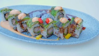Asian traditional food on a ceramic plate. Sushi Roll. Tasty vegetarian healthy dish. Slow motion horizontal video.