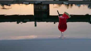 Tropical cocktail decorated with fresh watermelon at the seaside at sunset. Harbour with boats on the background. Vacation summer vibe. Full HD video. 