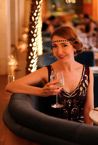 Woman in 1920 style clothes with a glass. Beautiful girl retro flapper style retro vintage roaring 20s.