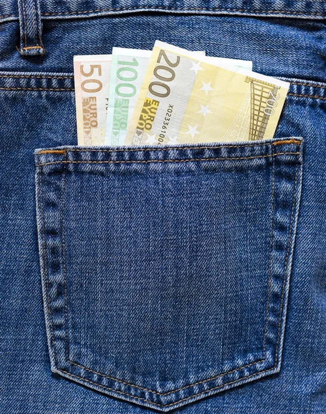 Billetes en euros en el bolsillo trasero de un vaquero azul . Imagen De Stock