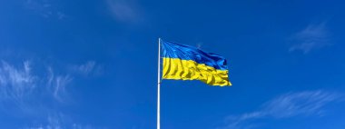 Mavi gökyüzüne karşı rüzgarla dolu bayrak direğinde Ukrayna bayrağı. Sembol ya da işaret. Ulusun Bağımsızlığı