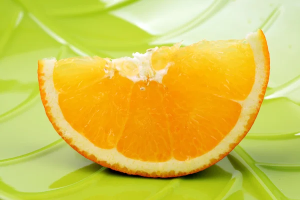 Πορτοκαλί σε ένα πράσινο πιάτο — Φωτογραφία Αρχείου