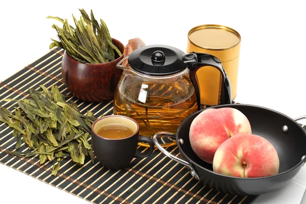 Peaches, cup and teapot of tea on white background — Stock Photo, Image