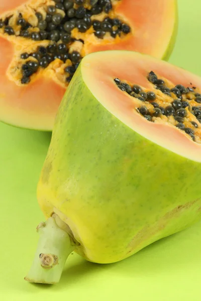 Плоды папайи, нарезанные наполовину изолированные на зеленом фоне . — стоковое фото