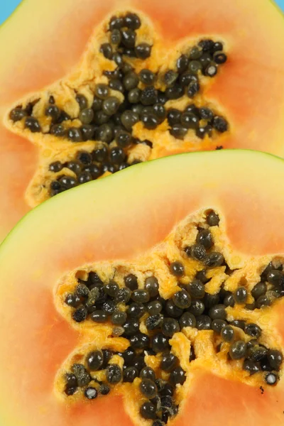 Fruta de mamão cortada ao meio isolada sobre fundo azul . — Fotografia de Stock