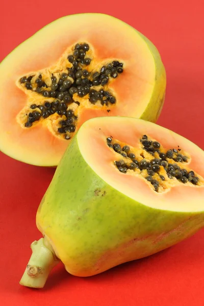 Плоды папайи, нарезанные наполовину изолированные на красном фоне . — стоковое фото
