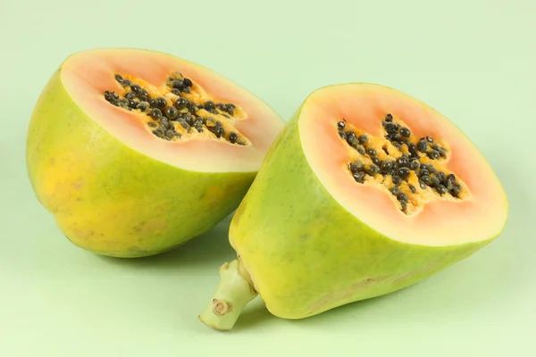 Papaya-Frucht in Scheiben geschnitten, halb isoliert auf grünem Hintergrund. — Stockfoto