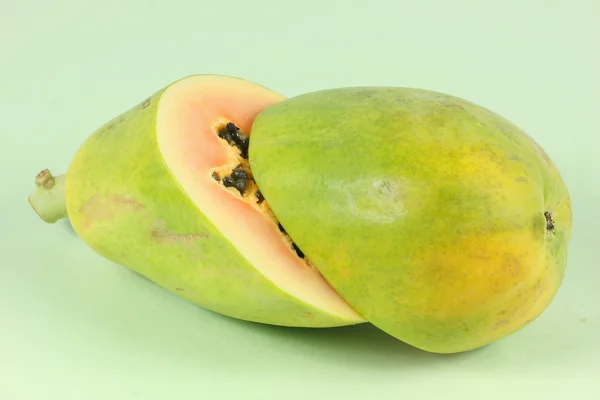 Papaya-Frucht in Scheiben geschnitten, halb isoliert auf grünem Hintergrund. — Stockfoto