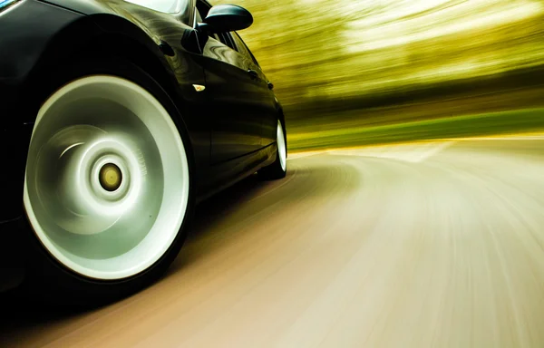 siyah lüks sedan hızlı sürüş görünümü.