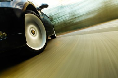 siyah lüks sedan hızlı sürüş görünümü.