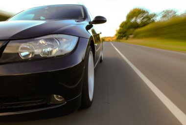 siyah lüks sedan hızlı sürüş görünümü.