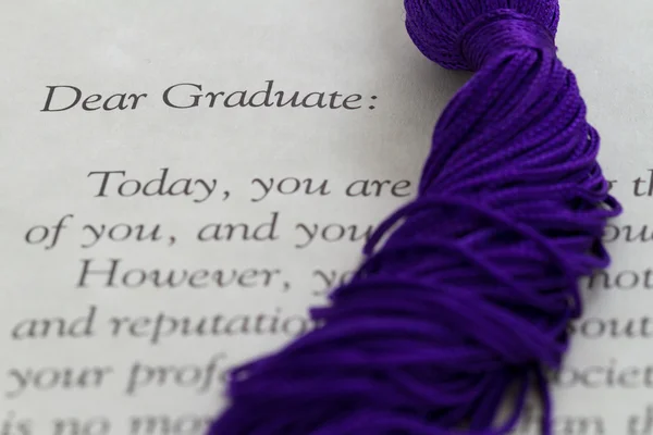 Cordones de borla apoyados en la parte superior del papeleo de graduación — Foto de Stock