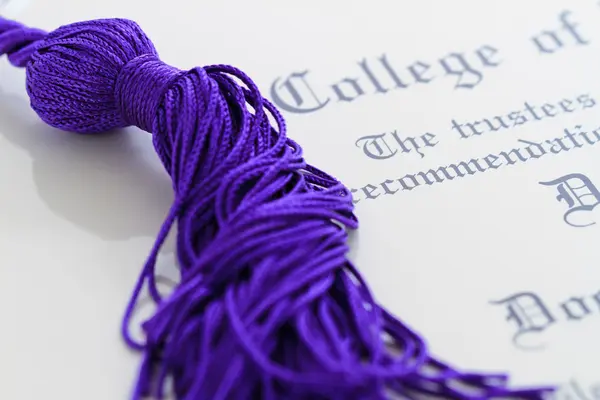 Cordones de borla apoyados en la parte superior del papeleo de graduación —  Fotos de Stock