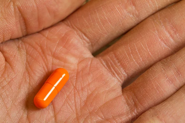 Elderly man holds a capsule in his hand, health-care signified — Stock Photo, Image