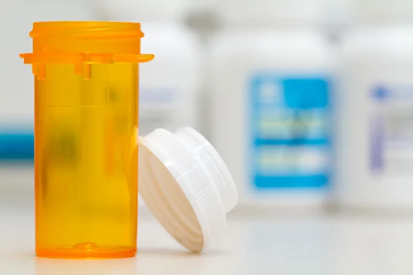 Pharmacy vial, empty, in a pharmacy, stock bottles in the background — Stock Photo, Image