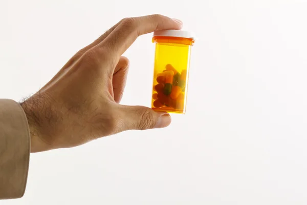Hand holding a pill bottle with capsules in it. isolated in studio. — Stock Photo, Image