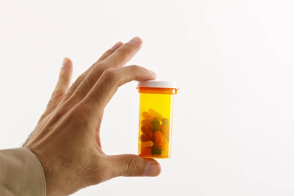 Hand holding a pill bottle with capsules in it. isolated in studio. — Stock Photo, Image