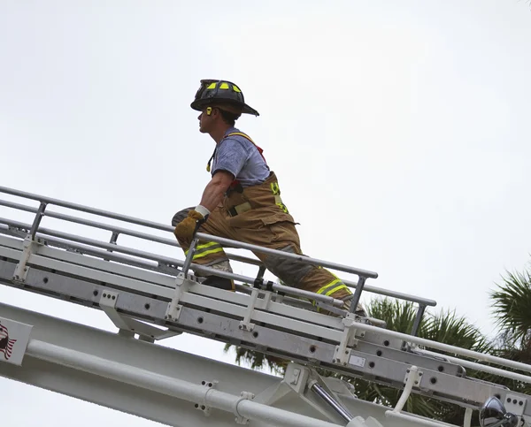 Fireman climbing a ladder to enter a building — Stock Photo, Image