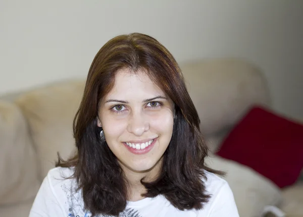 A young female adult sitting in front of the couch Stock Photo