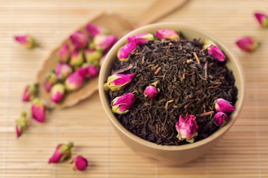 bir kase içinde gül tomurcukları ile siyah çay yaprakları