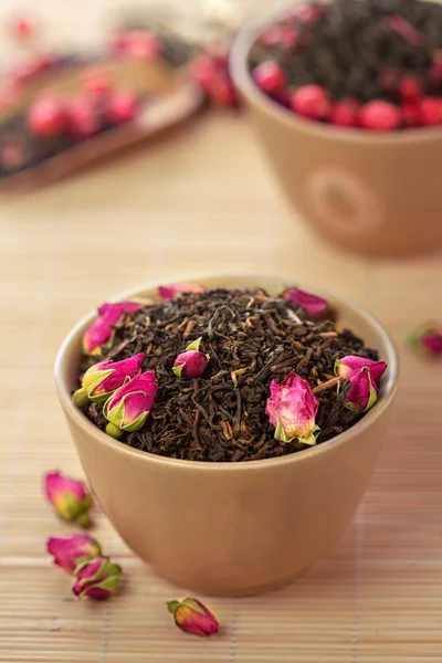 bir kase içinde gül tomurcukları ile siyah çay yaprakları