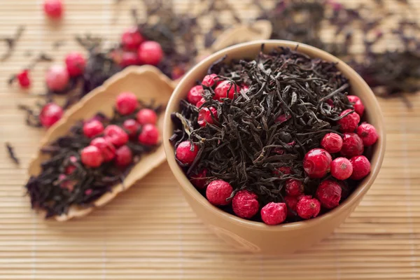 Black tea leaves with dry cranberries in a bowl — Stock Photo, Image