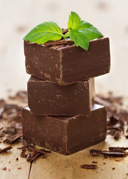 Closeup pieces of chocolate parts and mint leaves on wooden bac — Stock Photo, Image