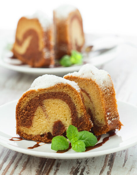 Vanilla and chocolate cake sliced with mint laves on wooden tab