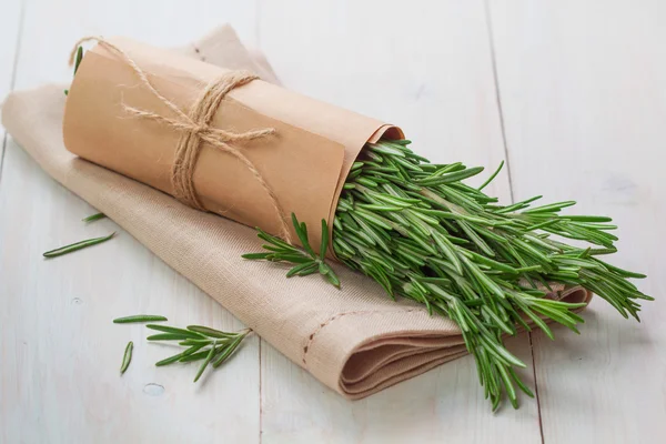 Bunch of fresh rosemary and napkin on wooden table — Stock Photo, Image