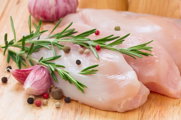 Petti di pollo crudi con pepe, aglio e rosmarino su c di legno — Foto Stock