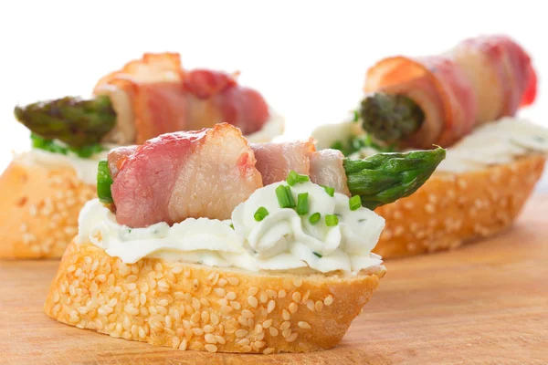 Appetizers - bread slices with bacon, asparagus and soft cheese — Stock Photo, Image