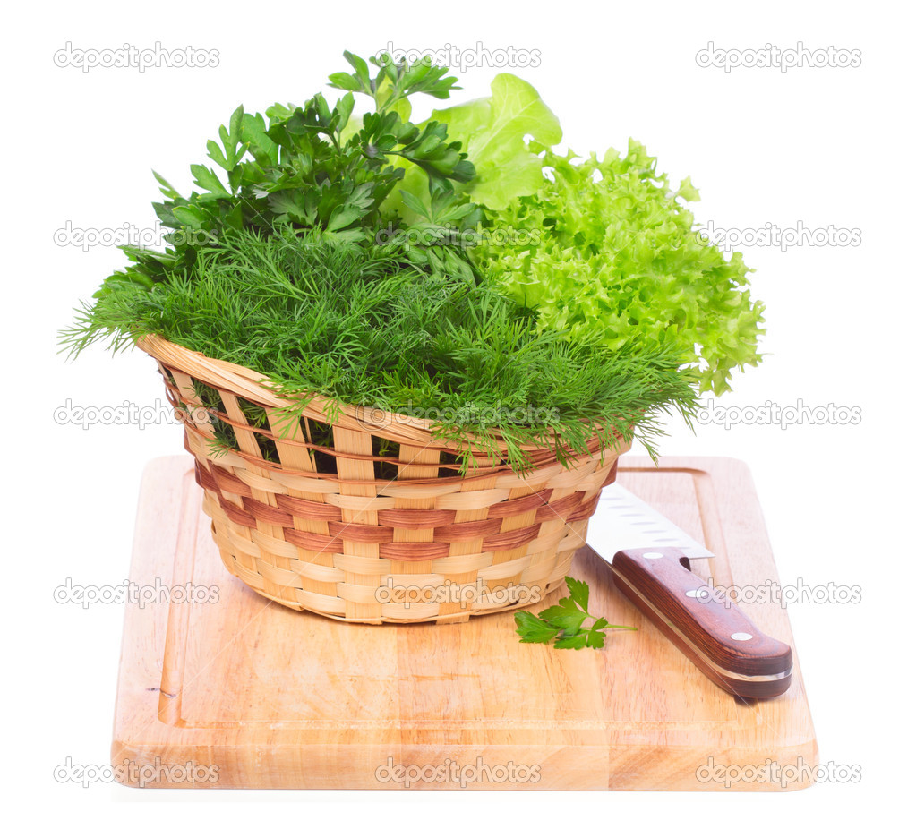 Green herbs in a basket on chopping board isolated on white back