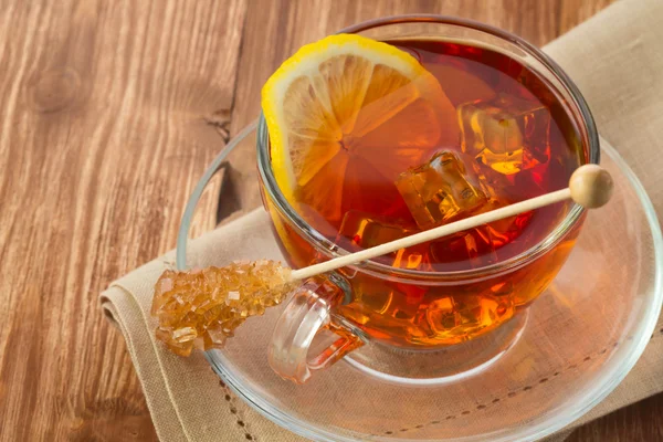 Cold tea with ice cube, lemon and sugar on wooden table — Stock Photo, Image