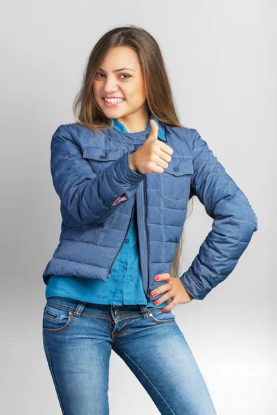 Jeune femme décontractée dans une veste montrant pouces vers le haut et souriant — Photo