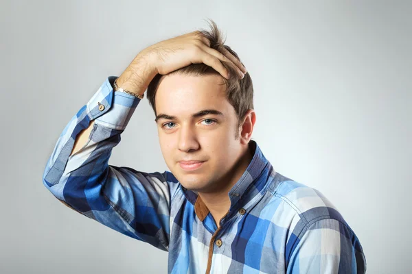 Portret van casual jonge man op zoek naar camera met hand op hoofd — Stockfoto