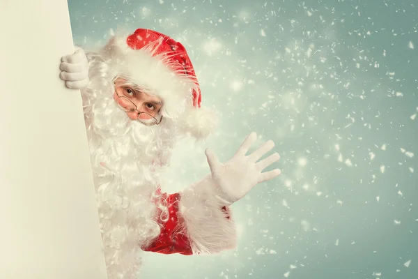 Babbo Natale sventola ciao da dietro banner bianco vuoto — Foto Stock
