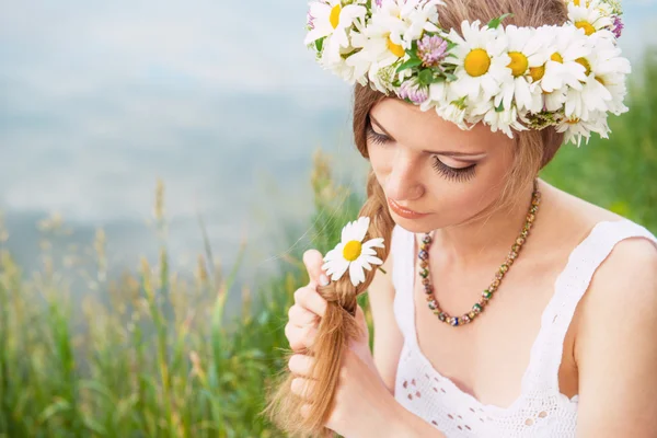 Leuke jonge vrouw met circlet van kamille vlechten haar haren op t — Stockfoto