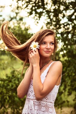 açık havada duran, bir çiçek tutan mutlu genç güzel kız