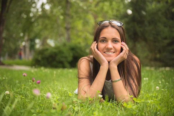 Portret van een jonge brunette vrouw genieten van het liggen op de gr — Stockfoto