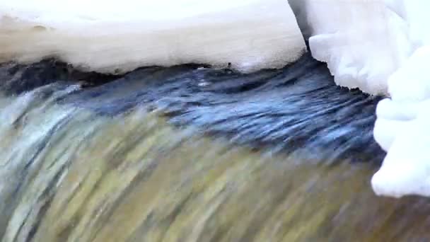 Ett klart vatten flödar under snön — Stockvideo
