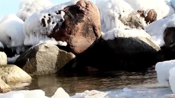 Sneeuw die betrekking hebben op de grote stenen op het strand — Stockvideo